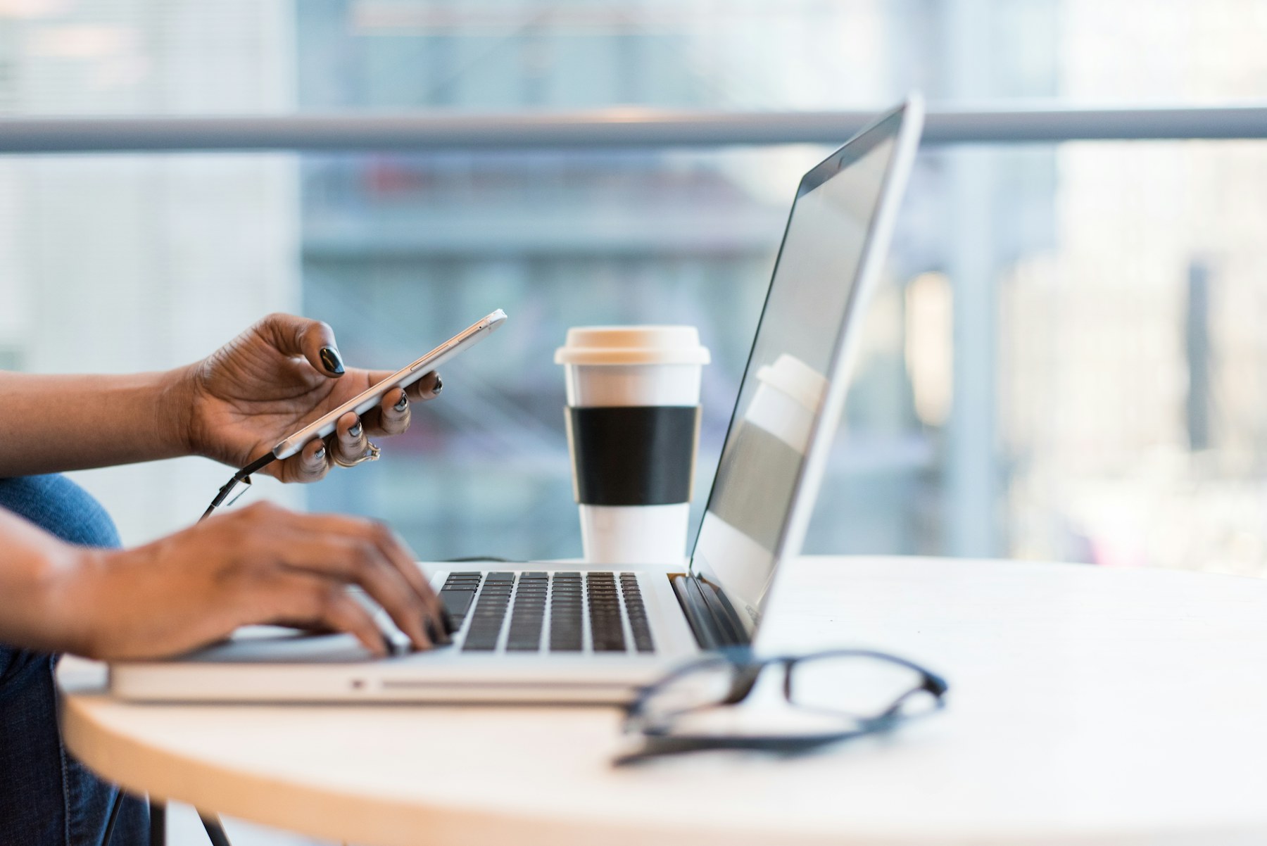 Professional working across a laptop and smartphone